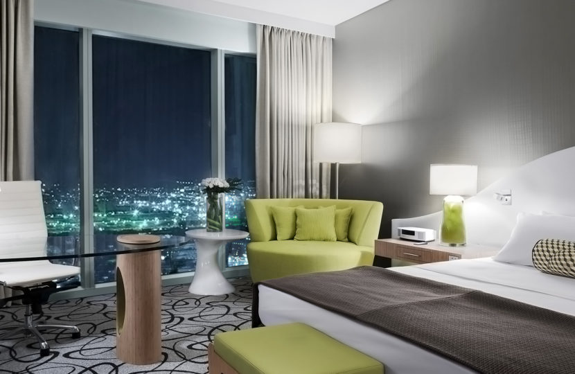 Modern hotel room with city view at night.