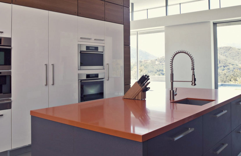 Modern kitchen with orange countertop and built-in appliances.